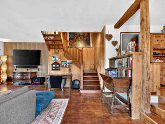 Experience rustic charm in this inviting living space, featuring a prominent wooden staircase and exposed beams that add warmth and character.
