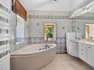 Indulge in relaxation in this spacious bathroom, featuring a luxurious corner bathtub perfect for unwinding.