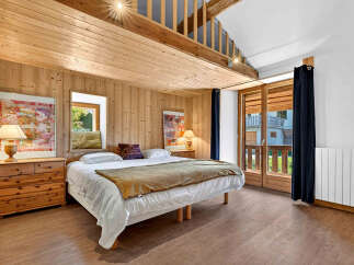 Experience rustic charm in this cozy bedroom featuring warm wood paneling and a comfortable bed.