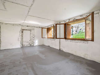 This unfinished room features a newly poured concrete floor and exposed stone walls, offering a blank canvas for renovation.