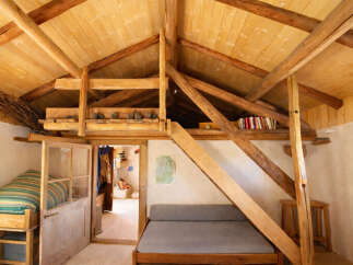 Discover this charming rustic cabin featuring a cozy loft space with exposed wooden beams and a sloped ceiling.
