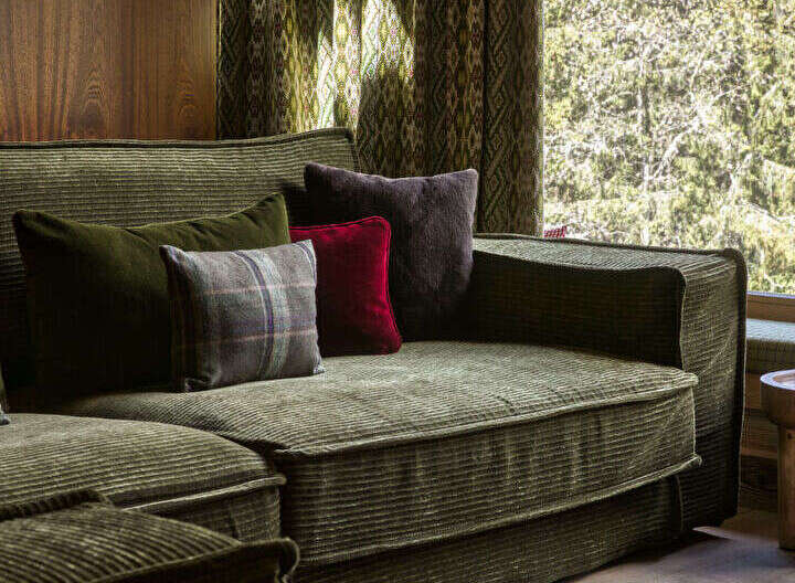 Experience rustic elegance in this living space, featuring a plush corduroy sectional sofa adorned with an assortment of textured throw pillows.