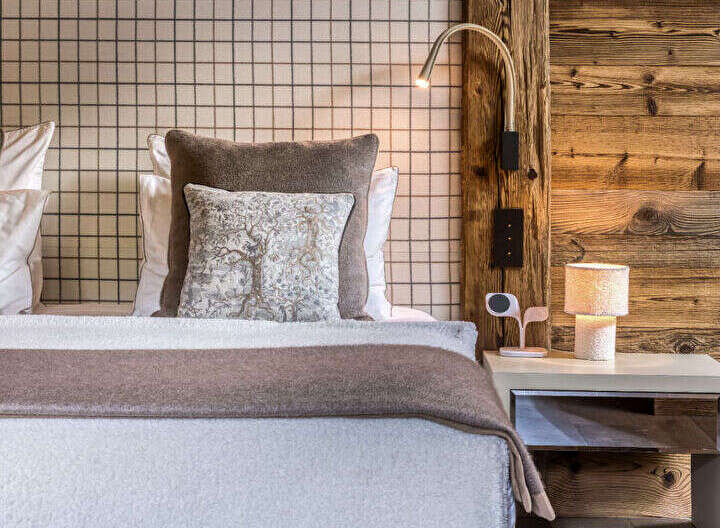 Experience rustic luxury in this charming bedroom, featuring a cozy bed adorned with plush pillows and a textured throw.