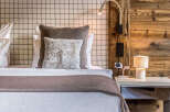 Experience rustic luxury in this charming bedroom, featuring a cozy bed adorned with plush pillows and a textured throw.