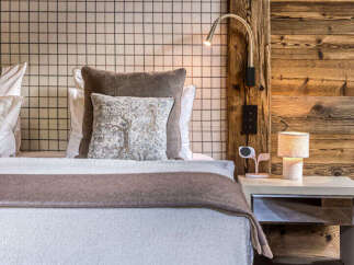 Experience rustic luxury in this charming bedroom, featuring a cozy bed adorned with plush pillows and a textured throw.