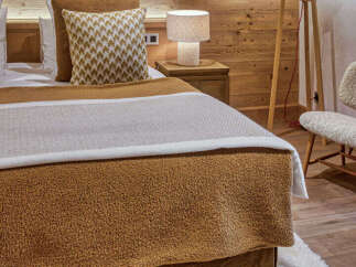 Experience rustic charm and cozy comfort in this beautifully appointed bedroom, featuring warm wood paneling and exposed beams.