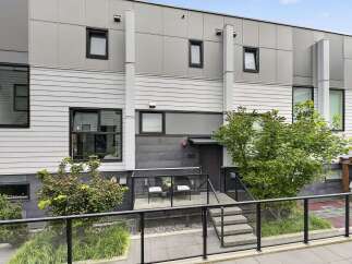 Discover modern living in this stunning townhouse featuring a sleek, contemporary facade with horizontal siding and large windows.