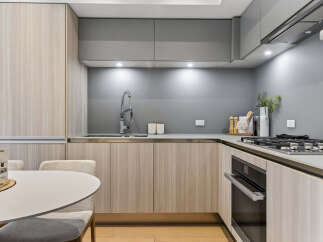 Experience modern living in this sleek kitchen featuring light wood cabinetry and a sophisticated grey backsplash.