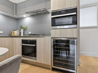 Experience modern luxury in this sleek kitchen, featuring integrated Miele appliances including a built-in oven and microwave.