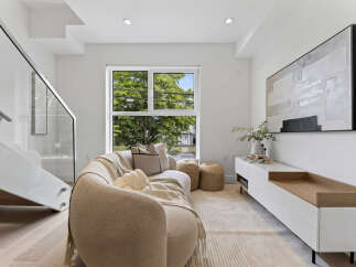 Experience modern living in this bright and airy living room, featuring a stylish curved sofa and a large window with lush green views.