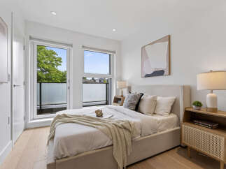Experience modern comfort in this beautifully appointed bedroom, featuring a plush bed, elegant side table with a stylish lamp, and a large window offering scenic views.