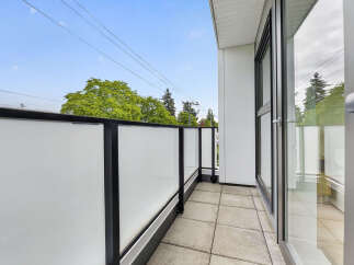 Enjoy the fresh air and scenic views from this modern balcony, featuring a sleek glass railing and durable tile flooring.