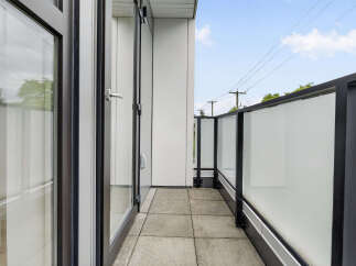 Enjoy the fresh air and city views from this modern balcony, featuring sleek glass railings and durable tile flooring.