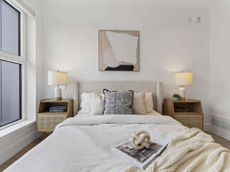 Experience modern comfort in this serene bedroom, featuring a plush king-sized bed adorned with crisp white linens and accent pillows.