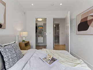 Experience modern comfort in this beautifully appointed bedroom, featuring a plush bed, a stylish abstract artwork, and convenient built-in closet space.