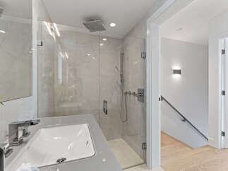 Experience modern luxury in this stunning bathroom featuring a spacious glass-enclosed shower with a rainfall showerhead and sleek chrome fixtures.