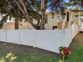 Discover this charming property featuring a private white vinyl fence, offering a sense of seclusion and security.