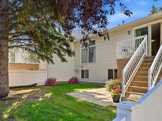 Enjoy outdoor living in this charming backyard featuring a spacious deck with white railings, perfect for entertaining.
