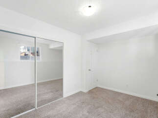 This spacious bedroom features a large mirrored closet, perfect for maximizing light and creating an illusion of more space.
