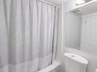 This bright and clean bathroom features a white bathtub with a grey and white striped shower curtain.