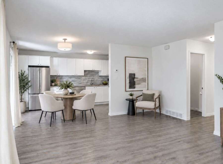 Discover modern living in this open-concept space featuring a sleek white kitchen with stainless steel appliances and a stylish dining area perfect for intimate gatherings.