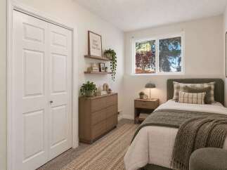 Discover this charming bedroom featuring a comfortable twin bed adorned with plush pillows and a cozy green throw blanket.