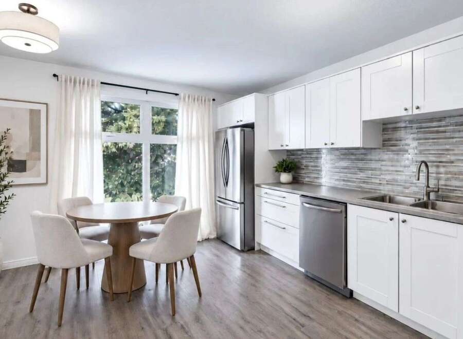 This bright and airy kitchen features a modern aesthetic with sleek white cabinetry and a striking mosaic tile backsplash.