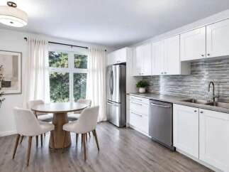 This bright and airy kitchen features a modern aesthetic with sleek white cabinetry and a striking mosaic tile backsplash.