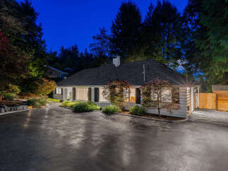 Nestled amongst mature trees, this charming home features a welcoming circular driveway and a beautifully landscaped front yard.