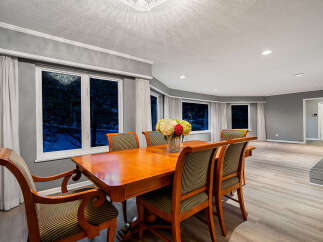 Experience elegant dining in this spacious room, featuring a large wooden table surrounded by upholstered chairs.