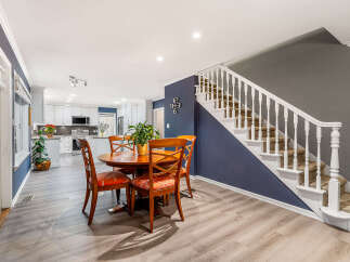 This inviting dining area features a warm wooden table surrounded by four chairs with patterned cushions, perfect for family meals.