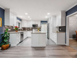 This stunning kitchen boasts crisp white cabinetry, sleek granite countertops, and a central island perfect for meal prep and casual dining.