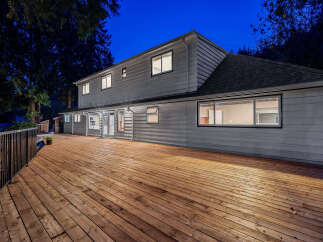 Experience outdoor living at its finest on this expansive wooden deck, perfect for entertaining or relaxing under the twilight sky.
