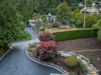 Discover this stunning property featuring a beautifully landscaped front yard with a winding driveway leading to a modern home.
