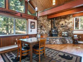Cozy dining area featuring a rustic stone fireplace with a wood-burning stove, perfect for gathering on chilly evenings.