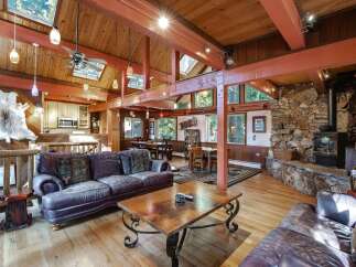 Experience rustic charm in this spacious living area, featuring a grand stone fireplace and exposed wooden beams.
