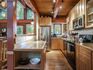 Experience rustic charm in this spacious kitchen featuring warm wood cabinetry and exposed beams.