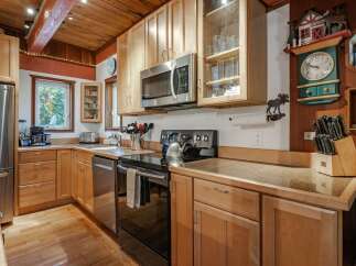 This charming kitchen boasts warm, natural wood cabinetry and a rustic wooden ceiling, creating a cozy and inviting atmosphere.