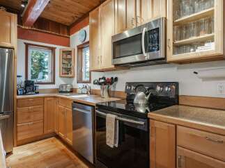 This charming kitchen features light wood cabinetry and a stainless steel refrigerator, microwave, and dishwasher.