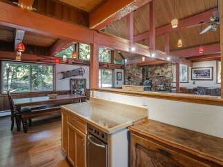 Experience rustic charm in this spacious dining and living area, featuring a large wooden dining table perfect for gatherings and a cozy stone fireplace as the centerpiece of the living room.