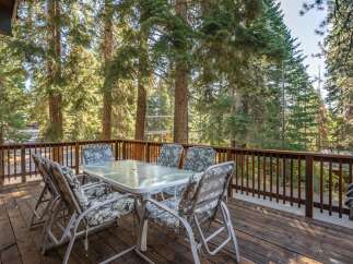 Enjoy outdoor dining and relaxation on this spacious deck, surrounded by the serene beauty of tall pine trees.