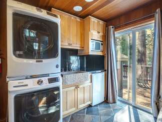 This charming cabin kitchen features a stacked Maytag washer and dryer for ultimate convenience.