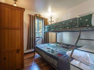 This charming bedroom features a sturdy wooden wardrobe and a cozy bunk bed setup, perfect for families or guests.