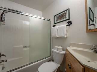 This charming bathroom features a clean and functional shower-tub combination with a sliding glass door.