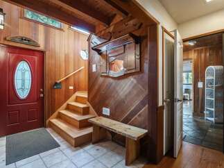 Step into a warm and inviting entryway featuring rich wood paneling and a striking red front door.