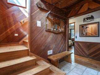 Step into a warm and inviting entryway featuring rich wood paneling and a charming staircase.
