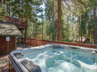Experience ultimate relaxation in this luxurious hot tub, perfectly situated on a spacious wooden deck surrounded by towering pine trees.