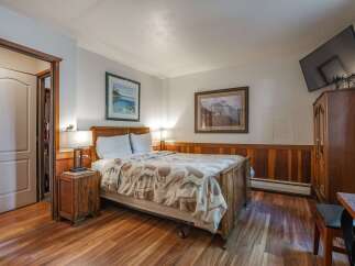 Discover this charming bedroom featuring a comfortable queen-size bed adorned with a unique fishing-themed comforter.