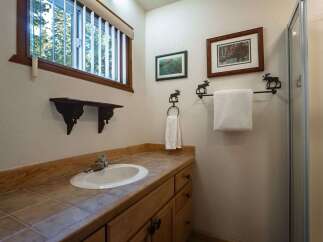 This charming bathroom features a rustic aesthetic with a wooden vanity and tiled countertop.
