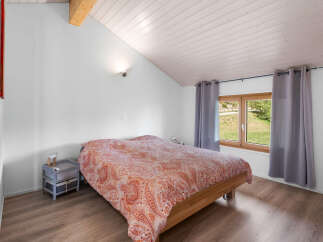 This charming bedroom features a comfortable bed with a vibrant paisley-patterned duvet, complemented by a rustic wooden nightstand.